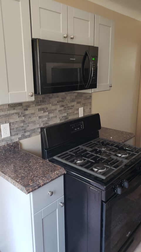 A black stove top oven sitting under a microwave.