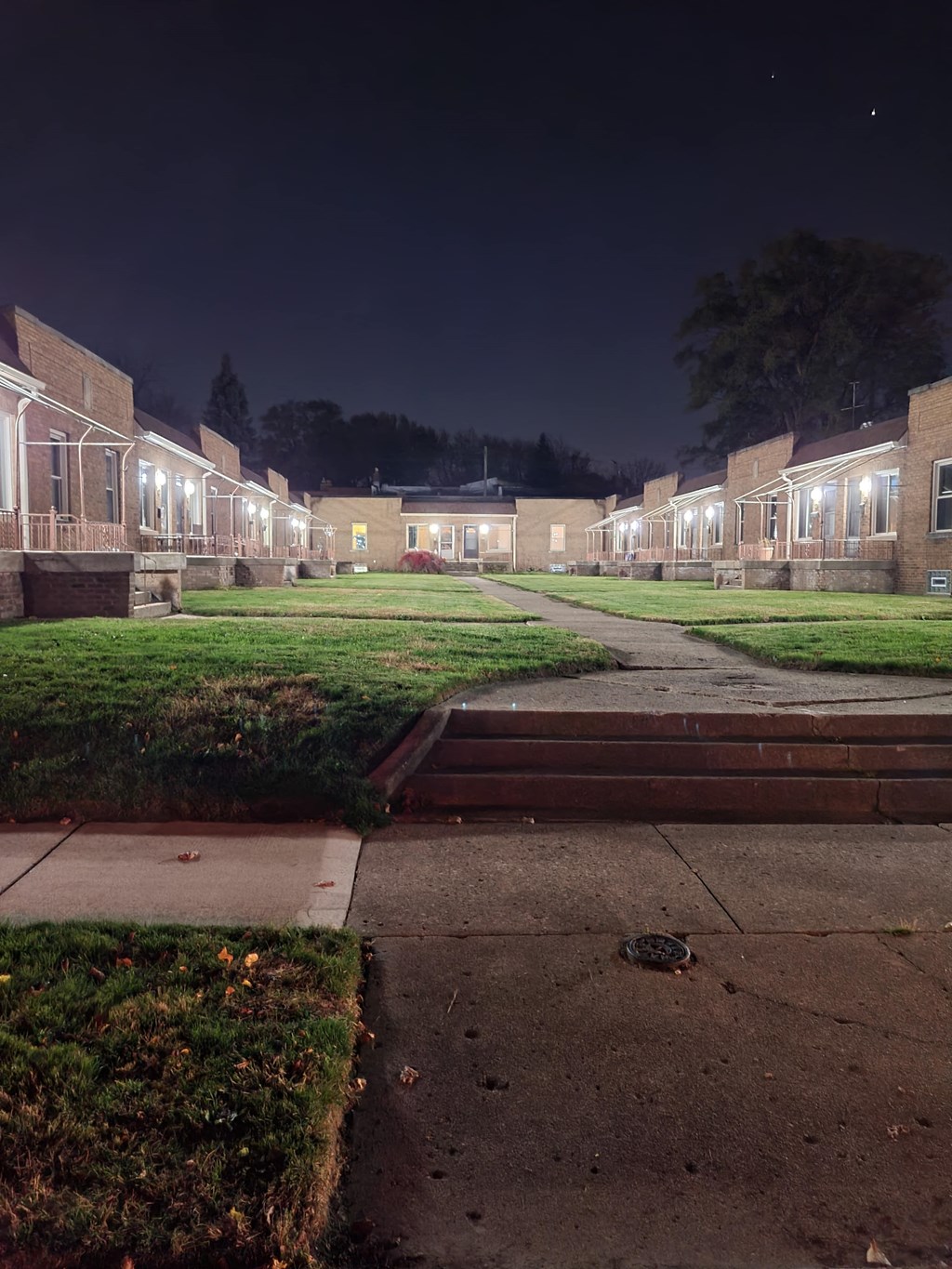 an empty street at night in a neighborhood with houses with lights