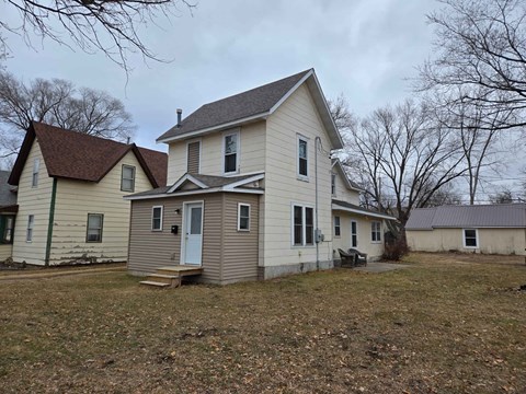A two-story house with a white front and a brown roof.