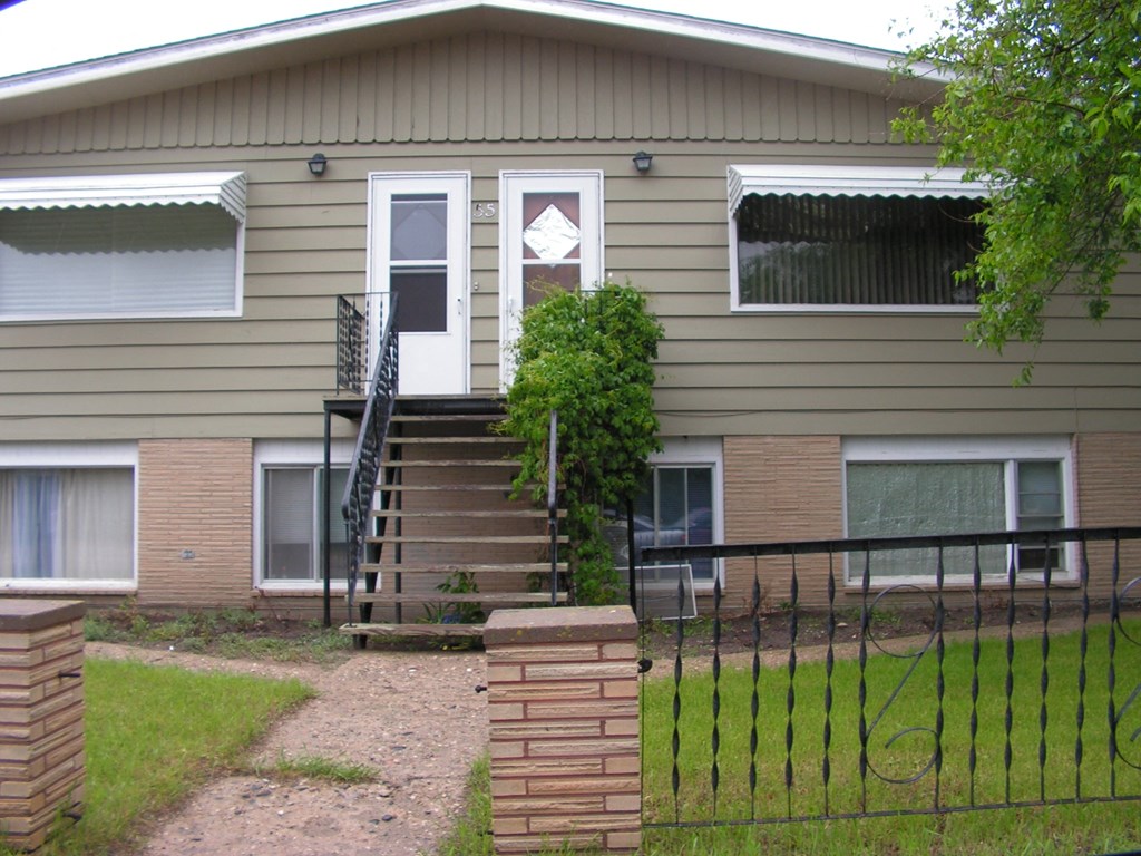 the front of a house with stairs and a black fence
