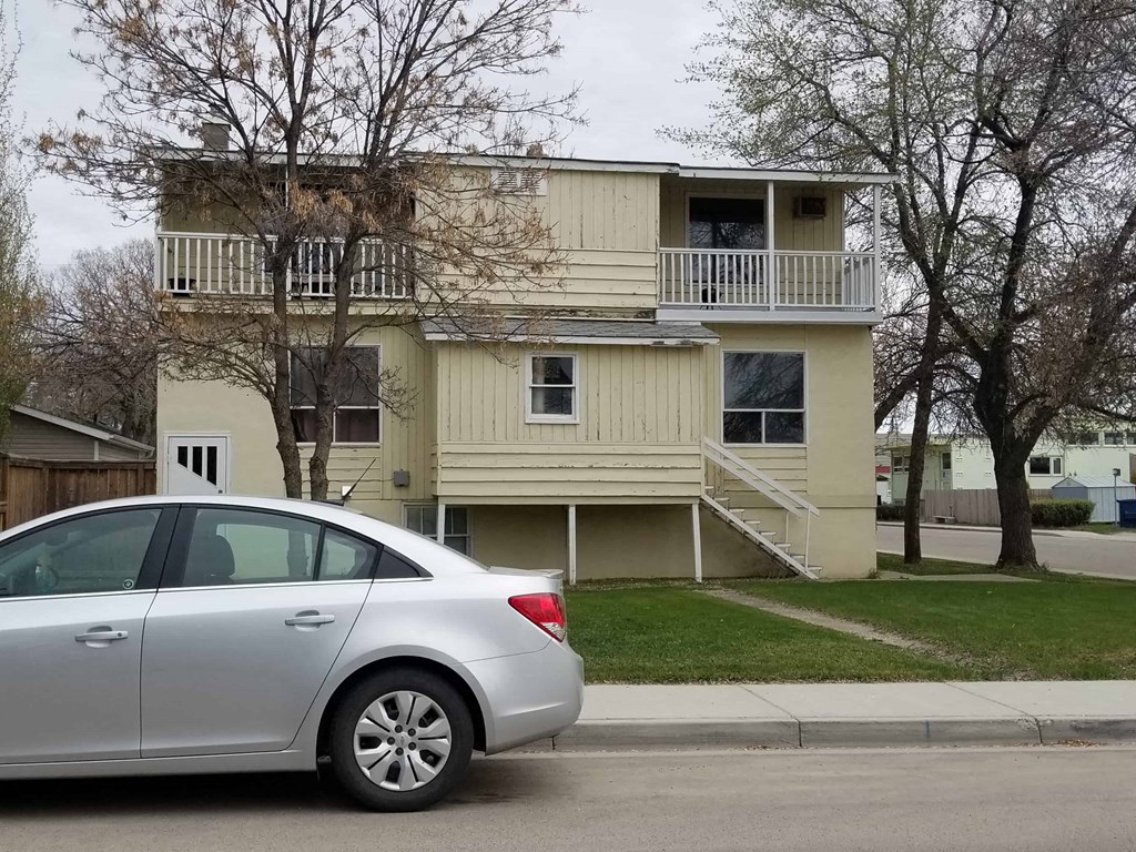 a car parked in front of a yellow house