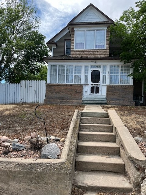 a house with steps in front of it and a white fence