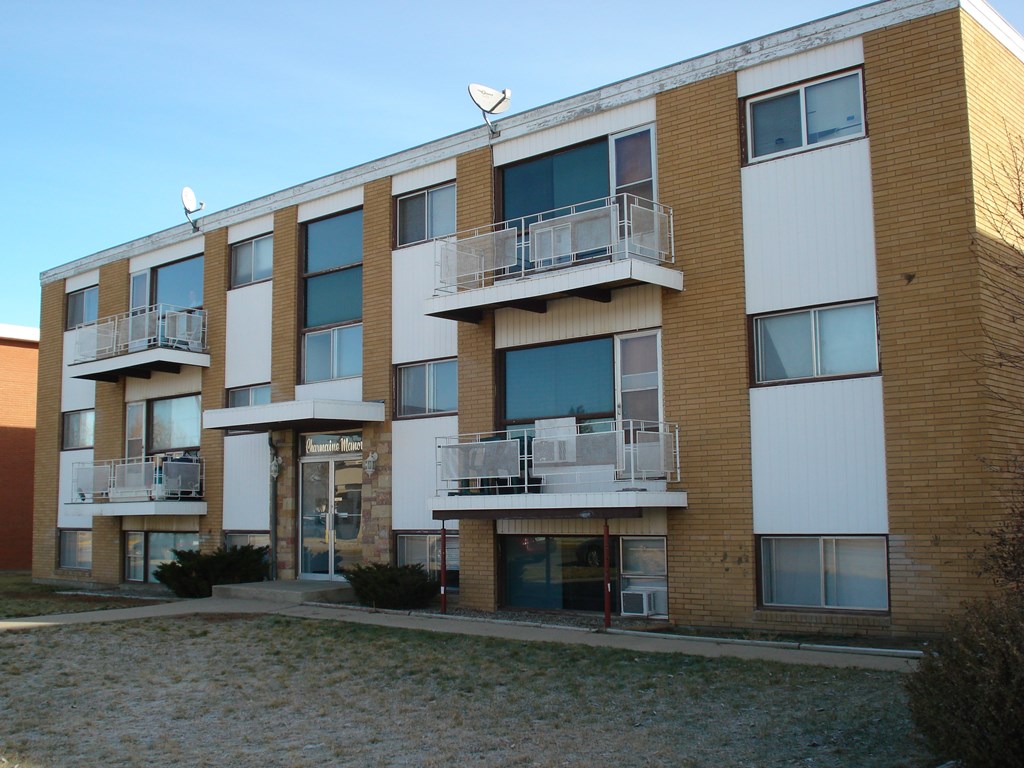 a brick apartment building with balconies and a sidewalk