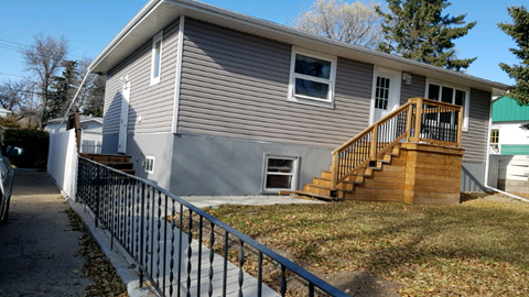 the front of a house with a wooden deck and stairs
