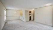 an empty living room with white walls and a kitchen