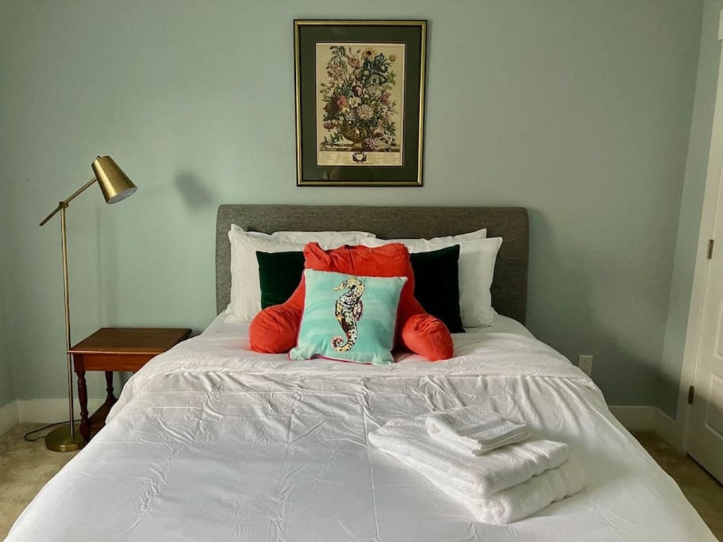 a bedroom with a bed with white sheets and colorful pillows