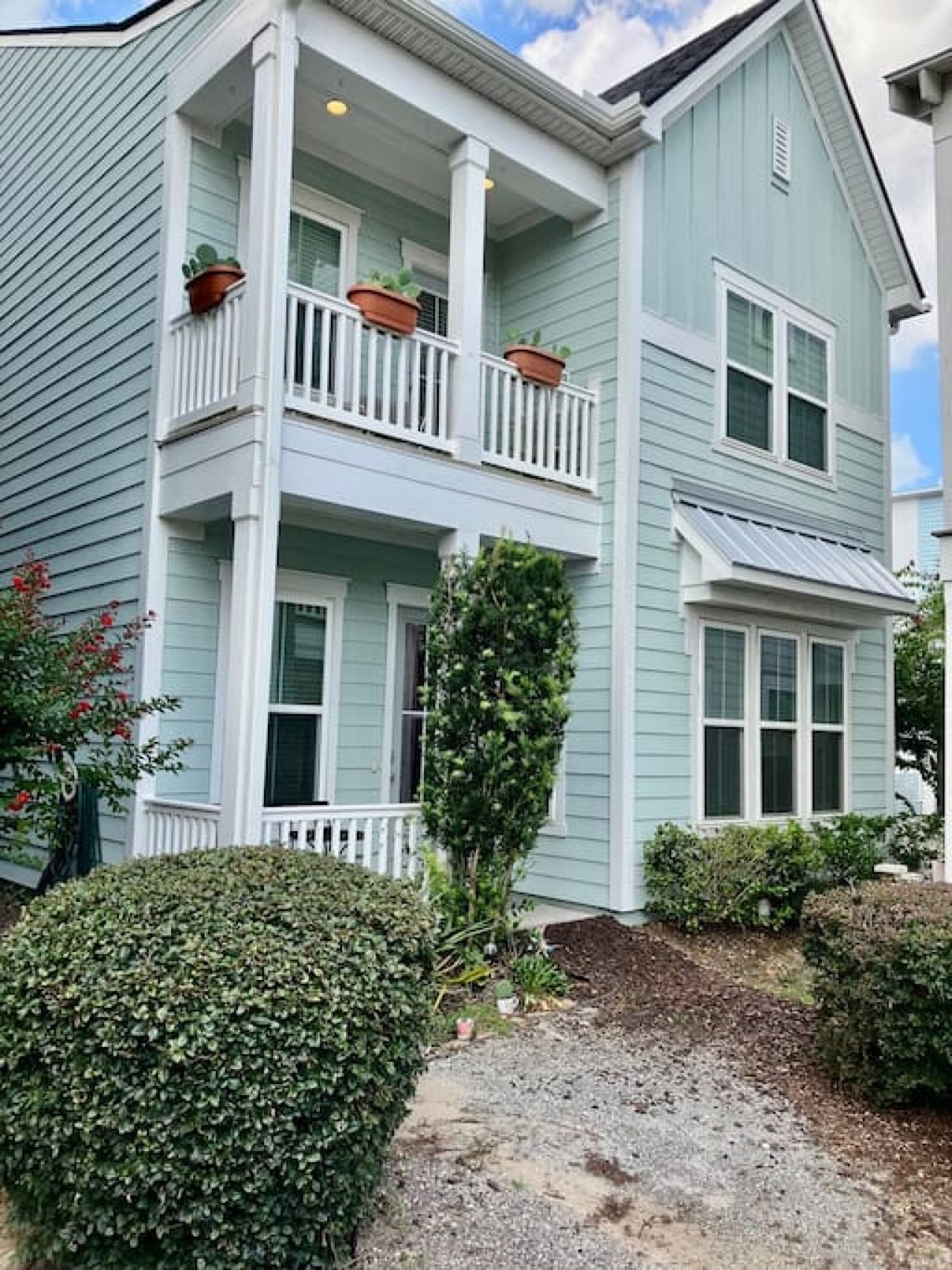 a blue house with a porch and plants on the balcony