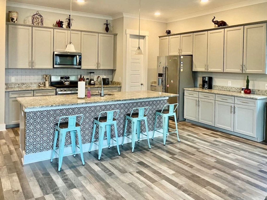 a kitchen with a large island with blue stools