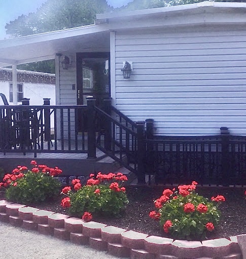 a house with a deck and flowers in front of it