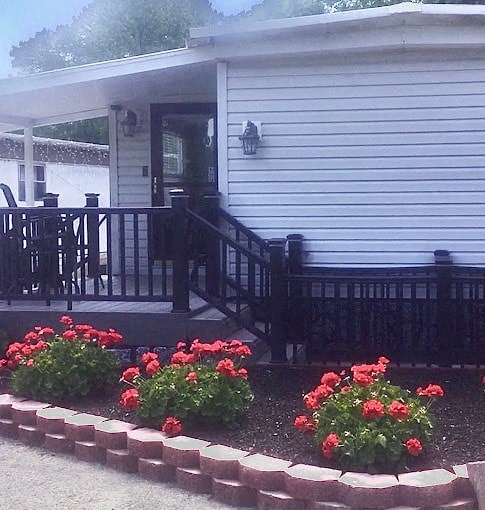 a house with a deck and flowers in front of it