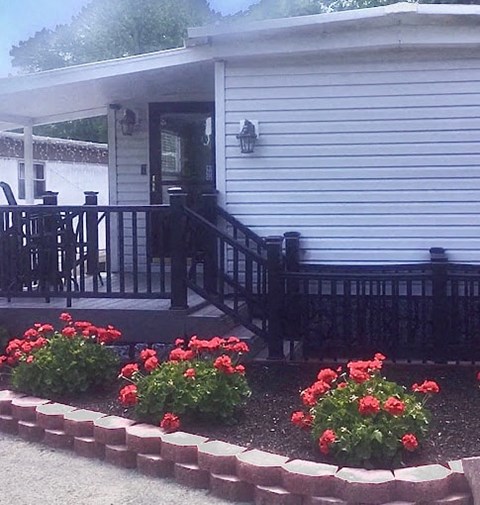 a house with a deck and flowers in front of it