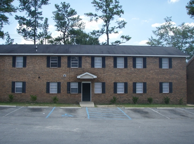 the front of a brick building with a parking lot