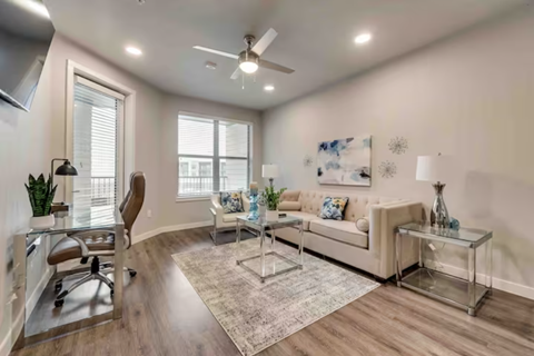 a living room with a couch and a desk and a ceiling fan