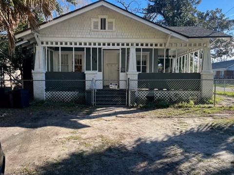 a small white house with a fence in front of it