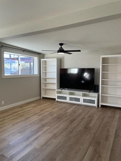 an empty living room with a tv and white shelves