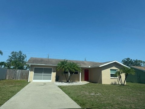 A house with a red door and a tree in front.