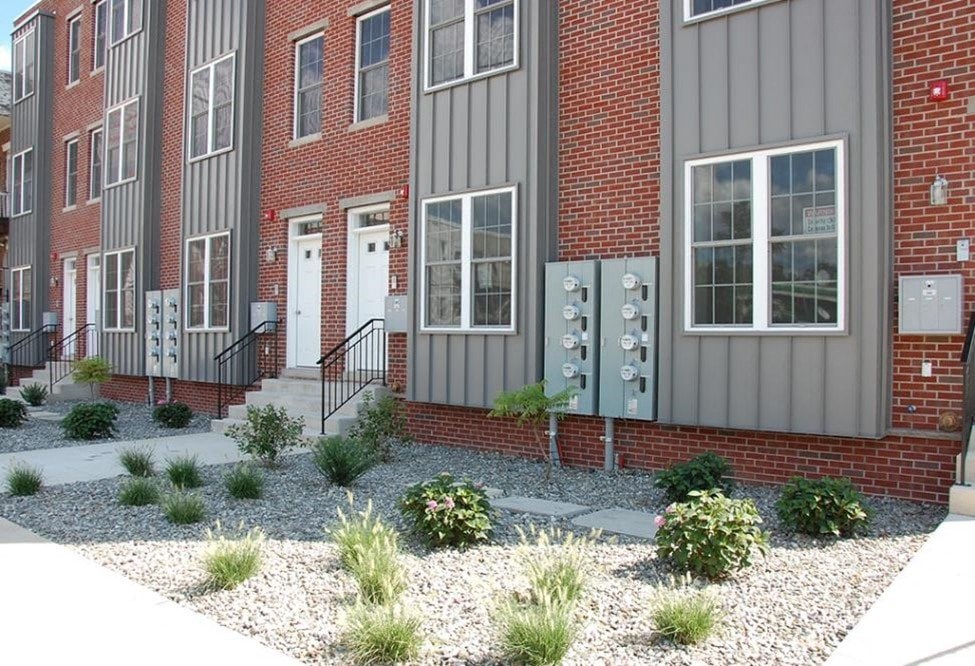 the front of a brick building with plants in front of it