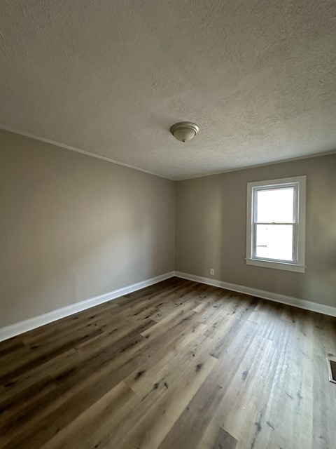 an empty living room with wooden floors and a window