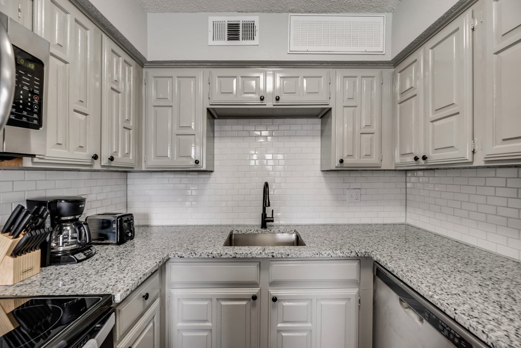 a white kitchen with white cabinets and a sink