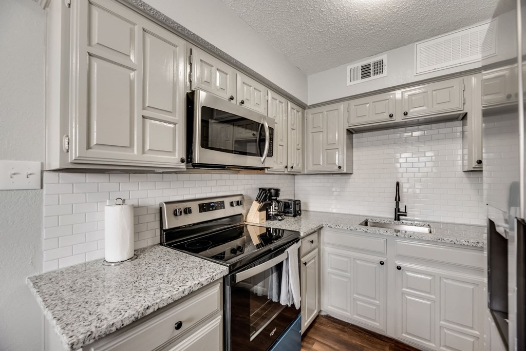 a kitchen with white cabinets and a stove and microwave