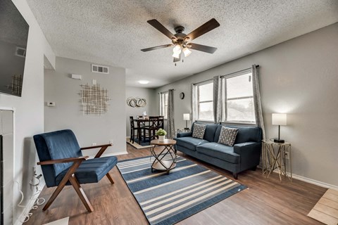 a living room with a couch and a chair and a ceiling fan