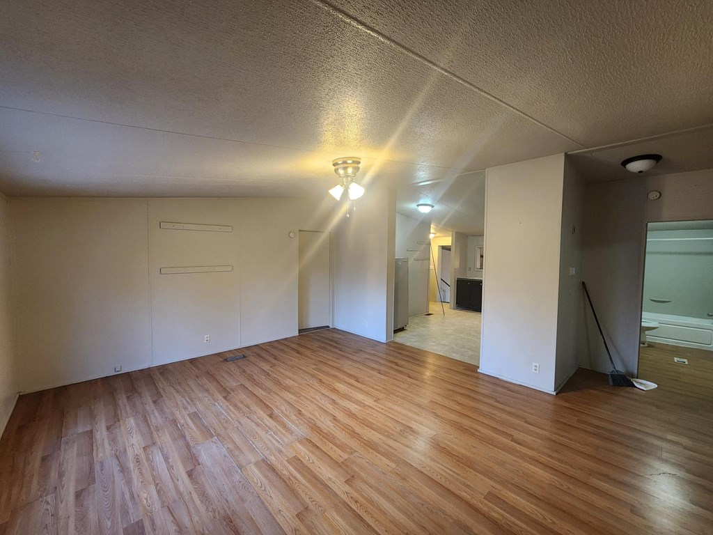 an empty living room with wood floors and white walls