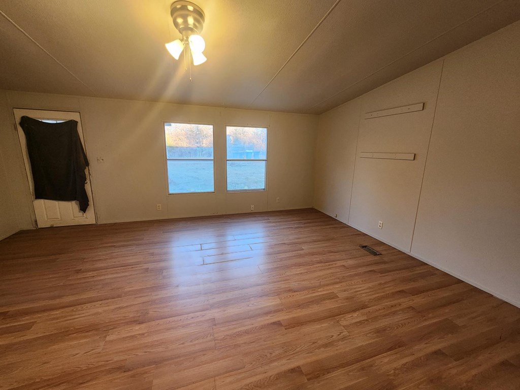 an empty room with a hard wood floor and a window