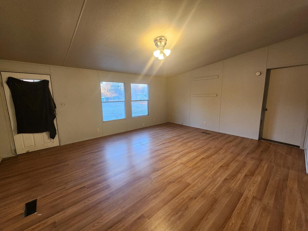 an empty living room with wood floors and a light on the ceiling