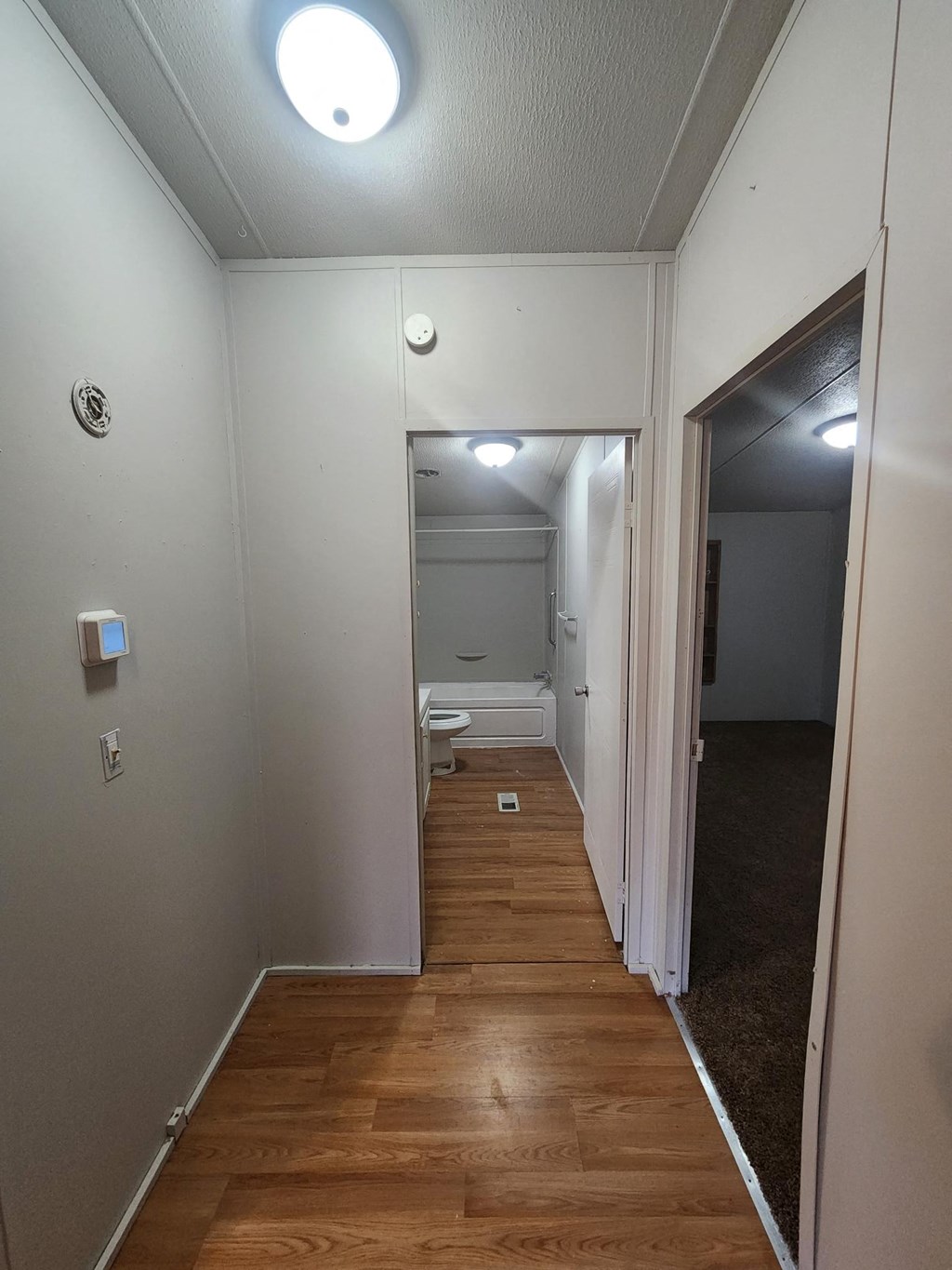 a small hallway with a door to a bathroom and a toilet