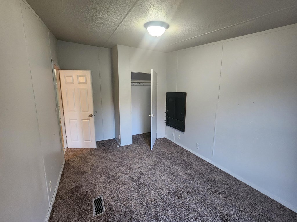 an empty living room with carpet and a tv