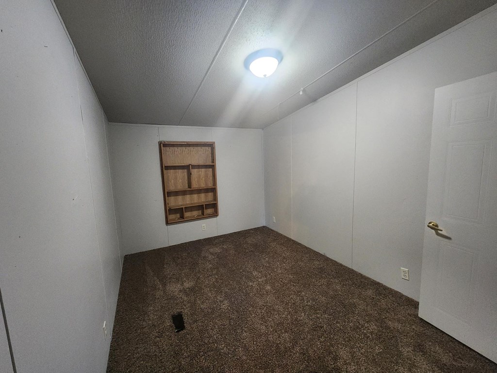 a room with a carpeted floor and white walls and a window