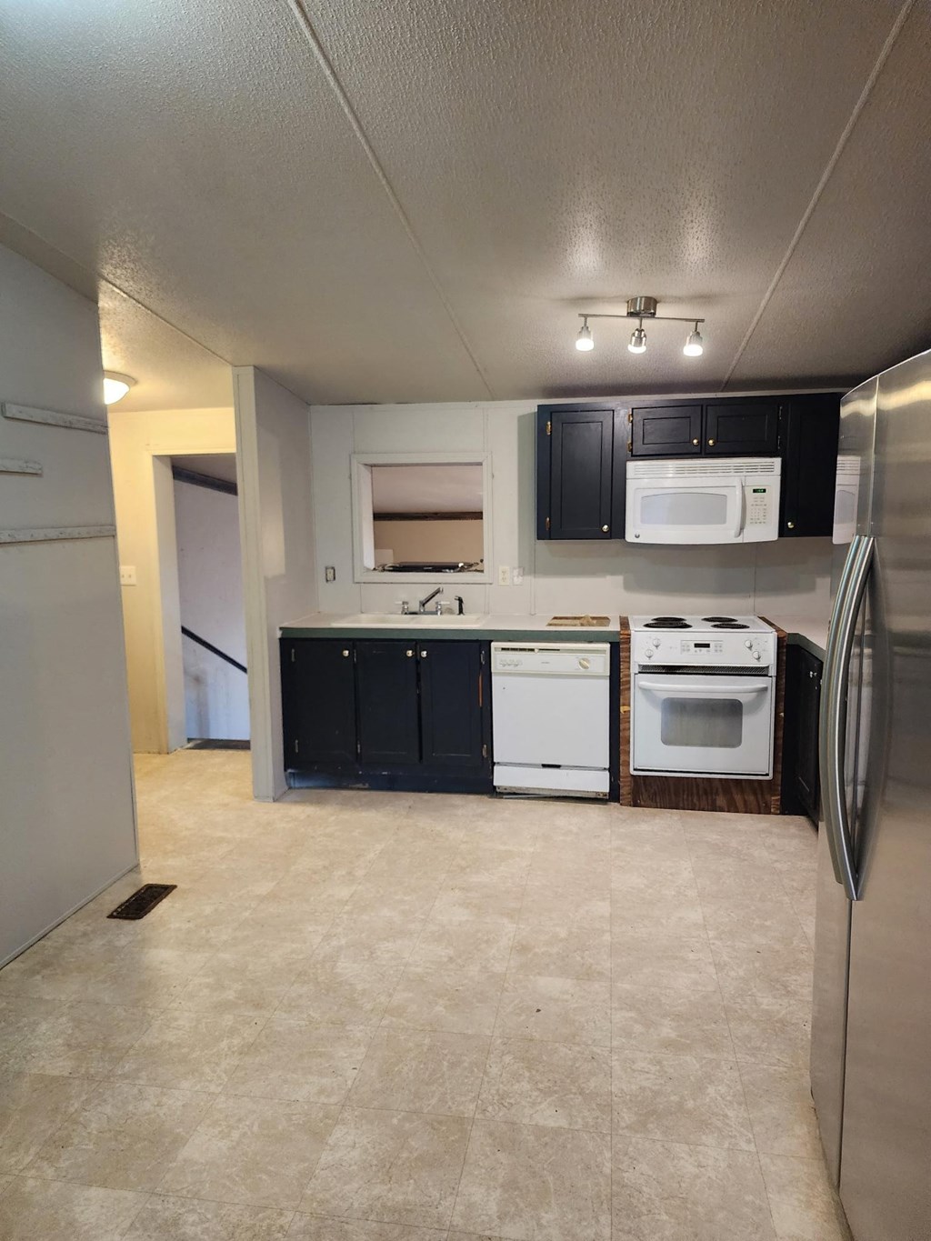 an empty kitchen with black cabinets and white appliances
