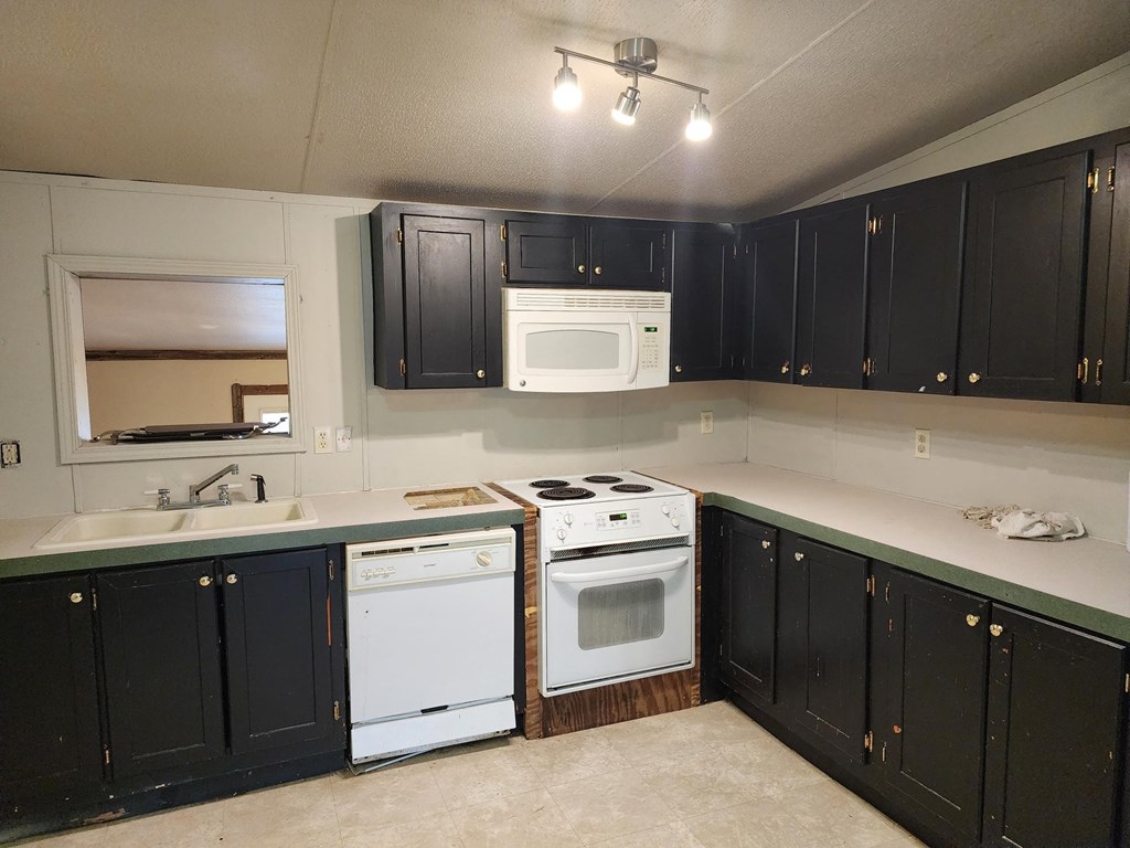 an empty kitchen with black cabinets and white appliances