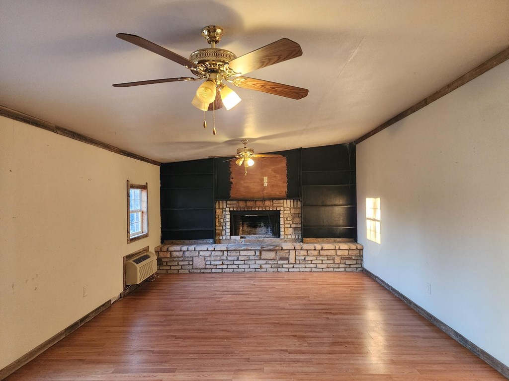 an empty living room with a ceiling fan and a fireplace