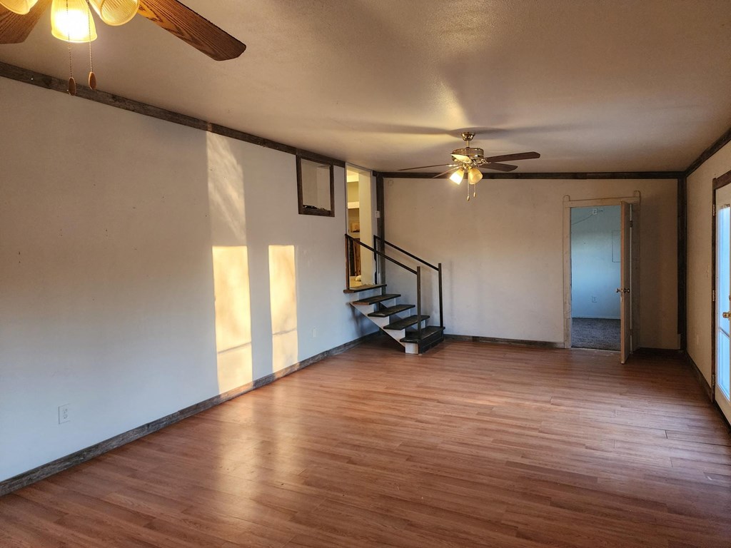 an empty living room with wooden floors and a ceiling fan
