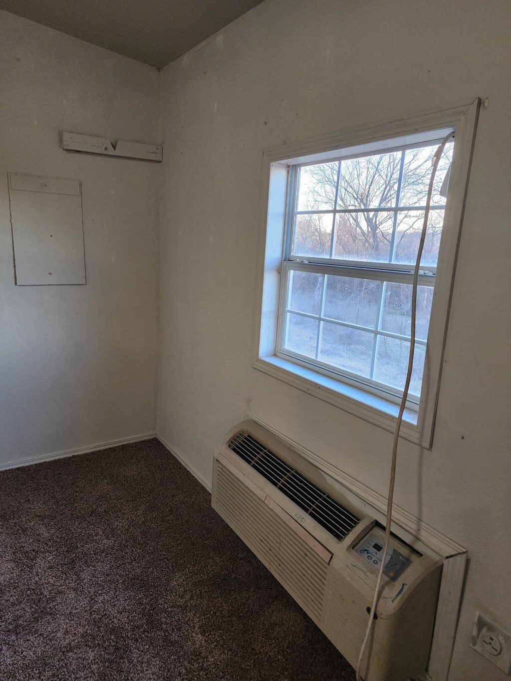 an empty room with a window and an air conditioner
