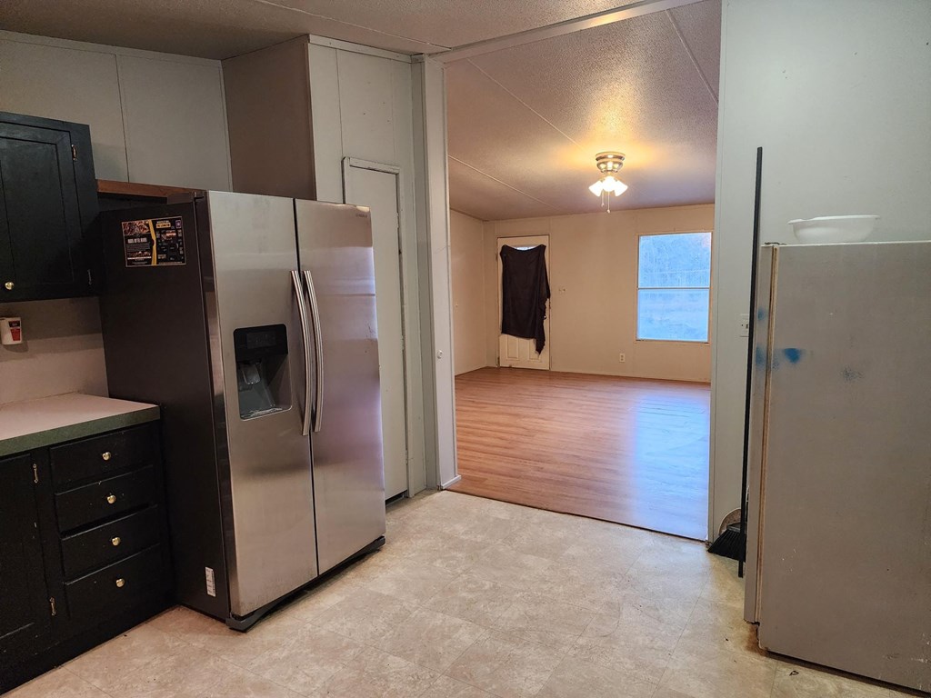 an empty kitchen with a refrigerator and a hard wood floor