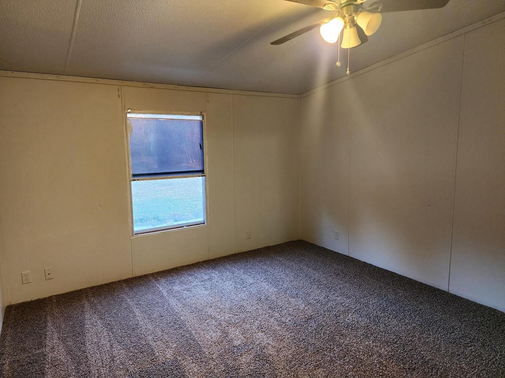 an empty room with a window and a ceiling fan