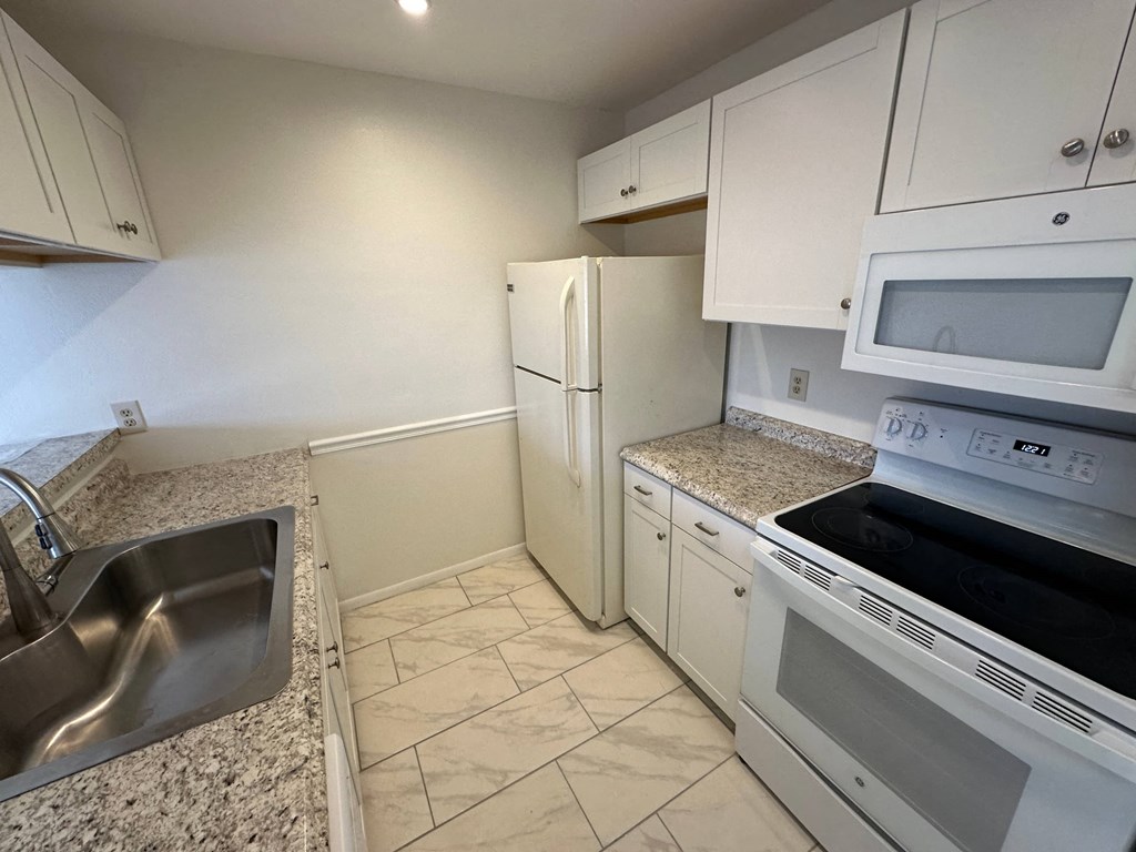 a kitchen with white appliances and granite counter tops