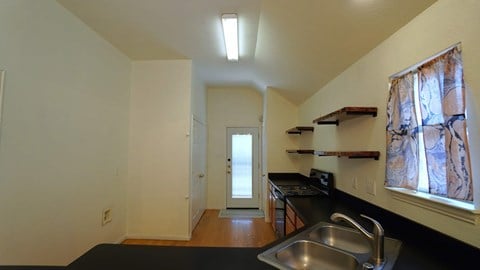 a kitchen with a sink and a door to a hallway