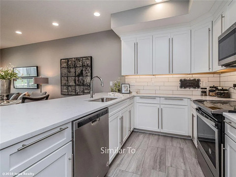 A modern kitchen with white cabinets and a wooden floor.