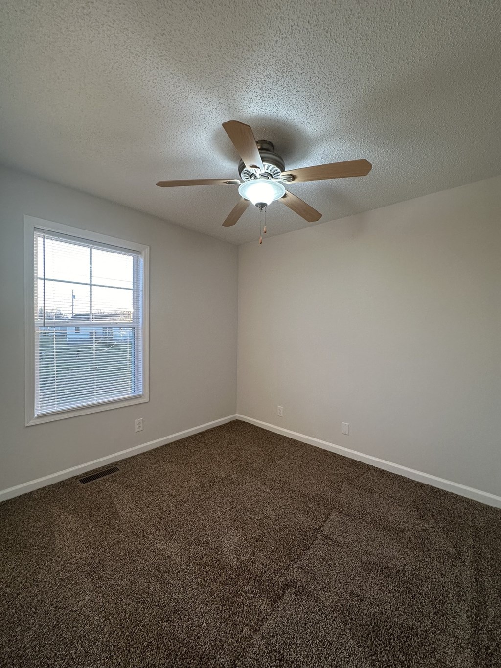 A room with a ceiling fan and carpeted floor.