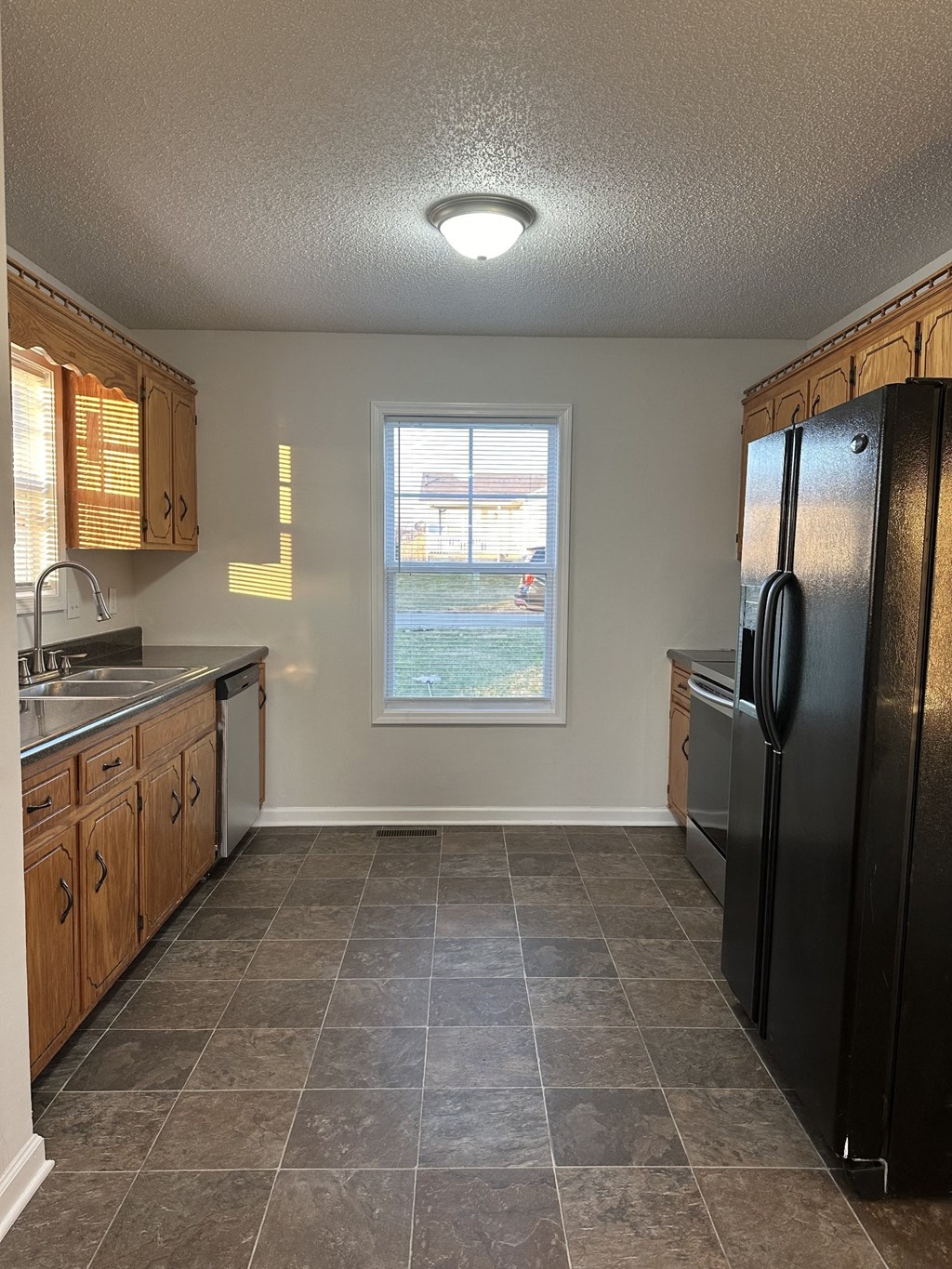 A kitchen with a black refrigerator and wooden cabinets.