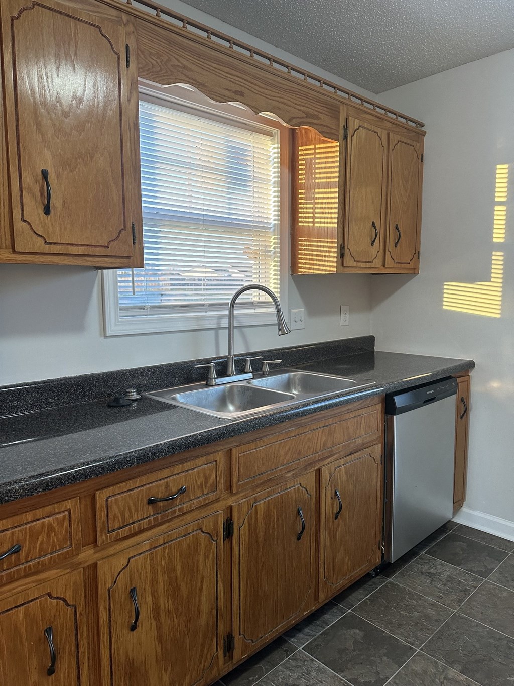 A kitchen with wooden cabinets and a black countertop.