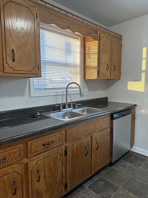 A kitchen with wooden cabinets and a black countertop.