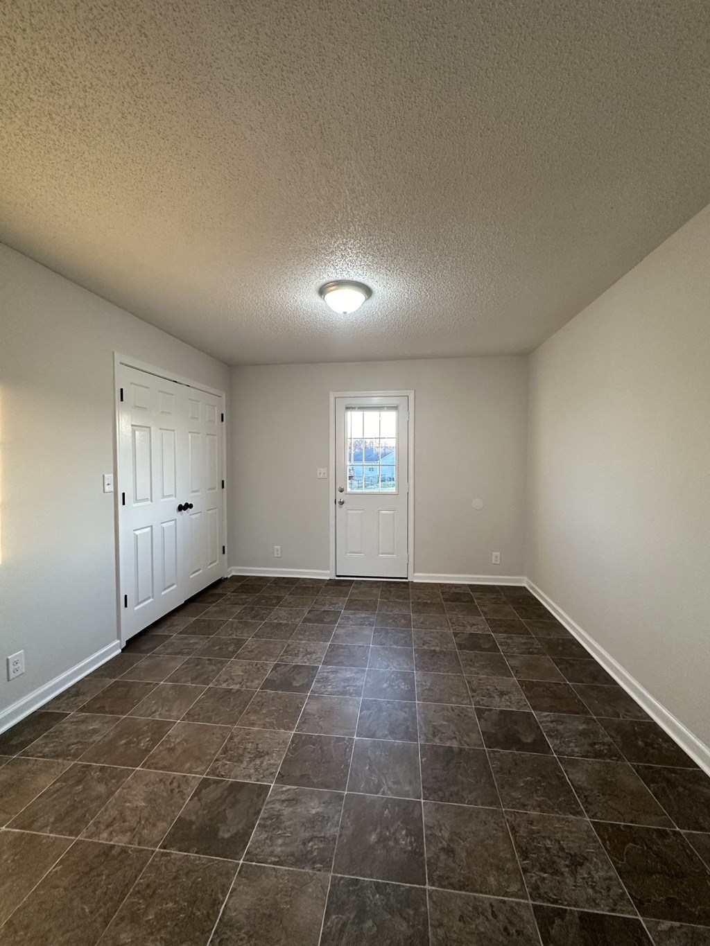 A room with tile flooring and a door leading to another room.