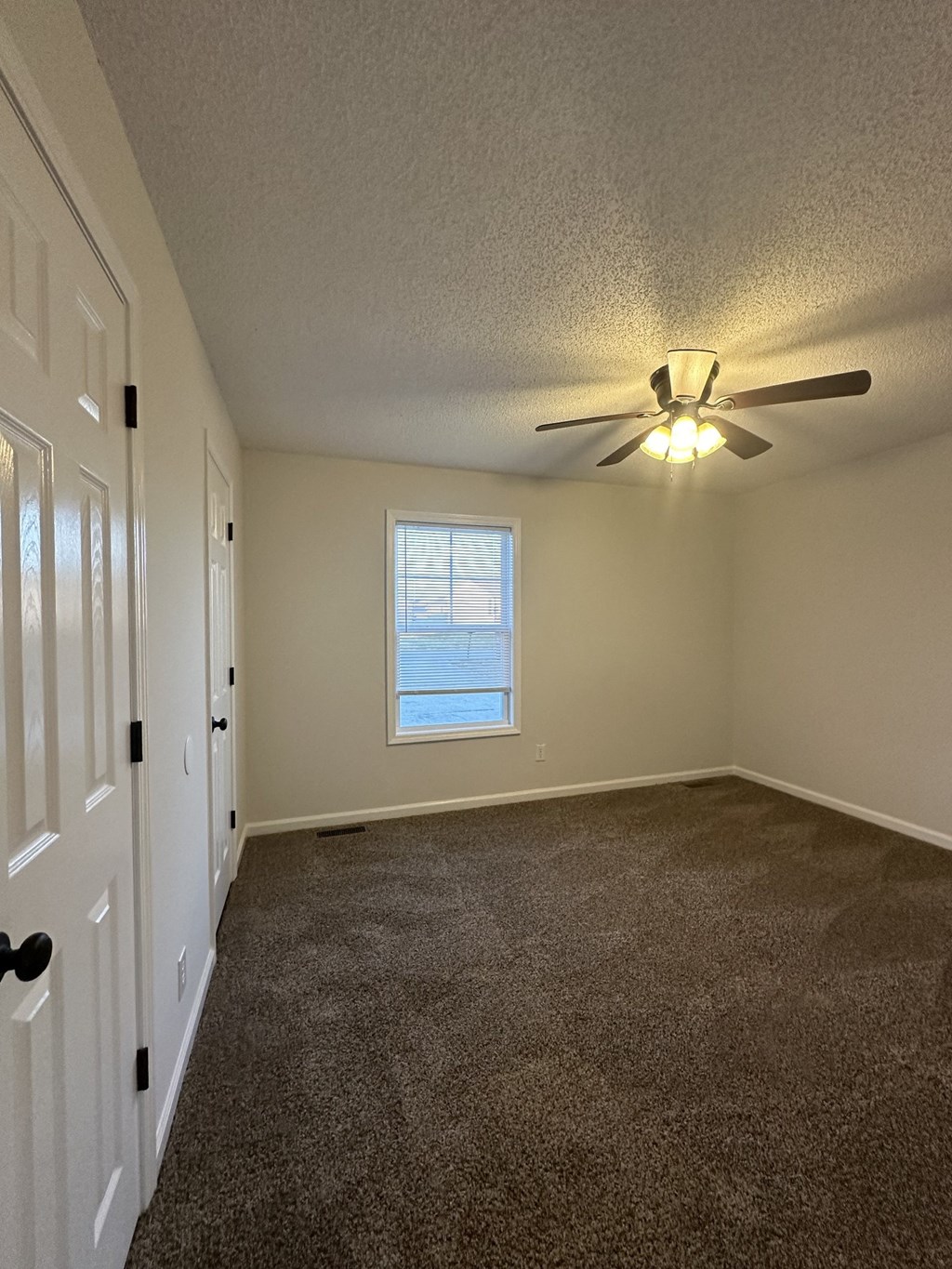 A room with a ceiling fan and a window.