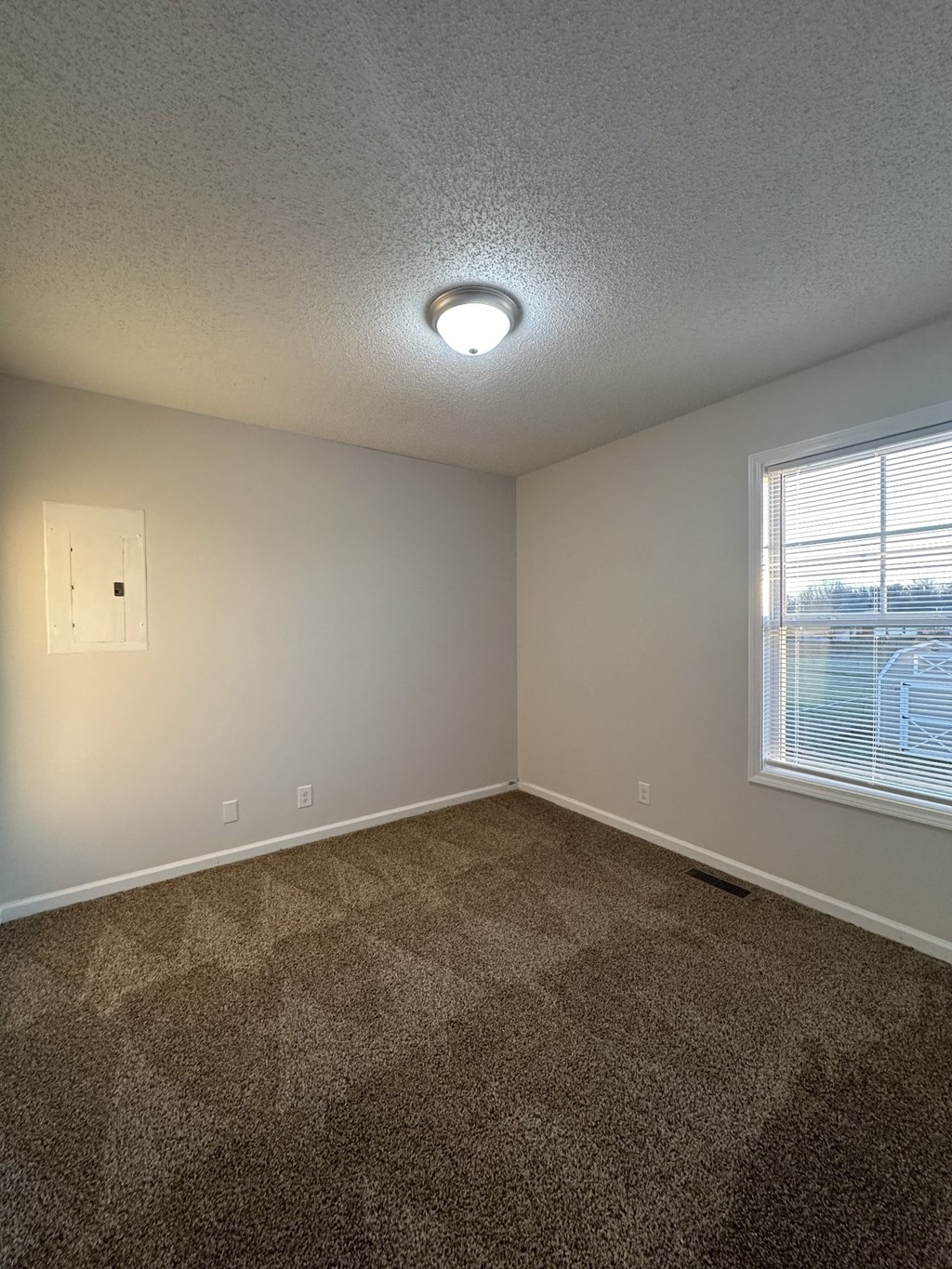 A room with a carpeted floor and a window with blinds.