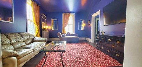 a living room with blue walls and a red rug