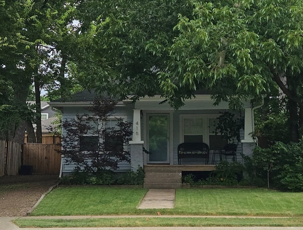a small white house with a lawn and trees